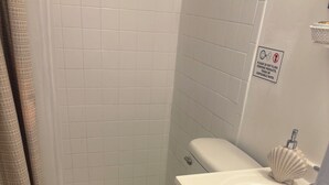 A bathroom with a toilet, sink, and a shower curtain. - Small studio (West Palm Beach)