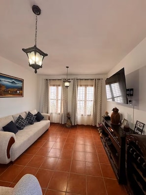 Ein Wohnzimmer mit einer Couch, einem an der Wand montierten Fernseher und einem Kamin.