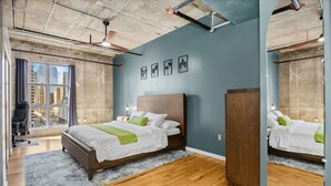 Une chambre à coucher avec un grand lit, une armoire en bois, un bureau et une fenêtre donnant sur la ville.