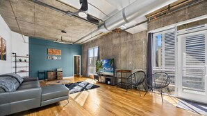 Un salon moderne avec un canapé, un meuble pour appareils multimédias et une grande fenêtre.