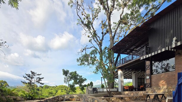 A swimming pool with stone walls, a covered outdoor seating area, and a view of the surrounding landscape. - Alpina Montecarlo (Copán Ruinas)