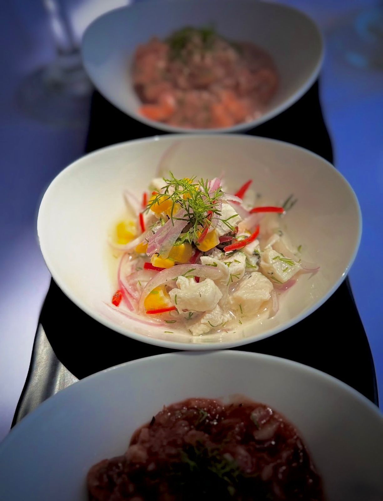 Three bowls of food on a table.