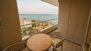 A balcony with a round table and wicker chairs, overlooking a coastal cityscape. - Luxury Apartment Suite in Santa Marta | Ocean View (Santa Marta)