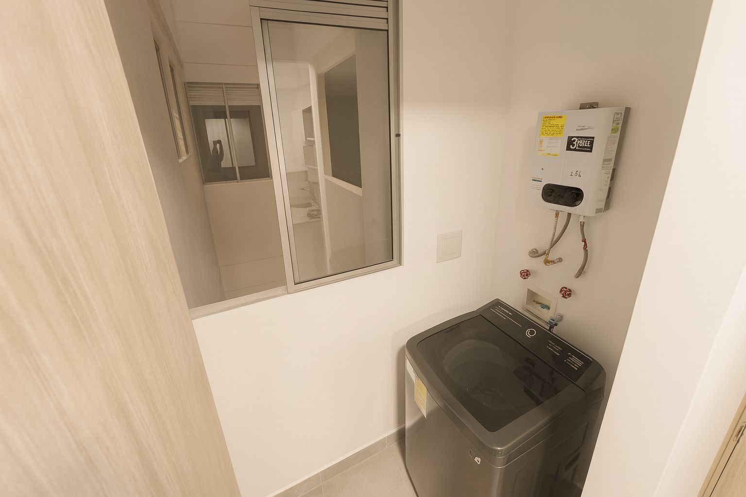 Una sala de lavandería con lavadora, un espejo y un calentador instalado en la pared.