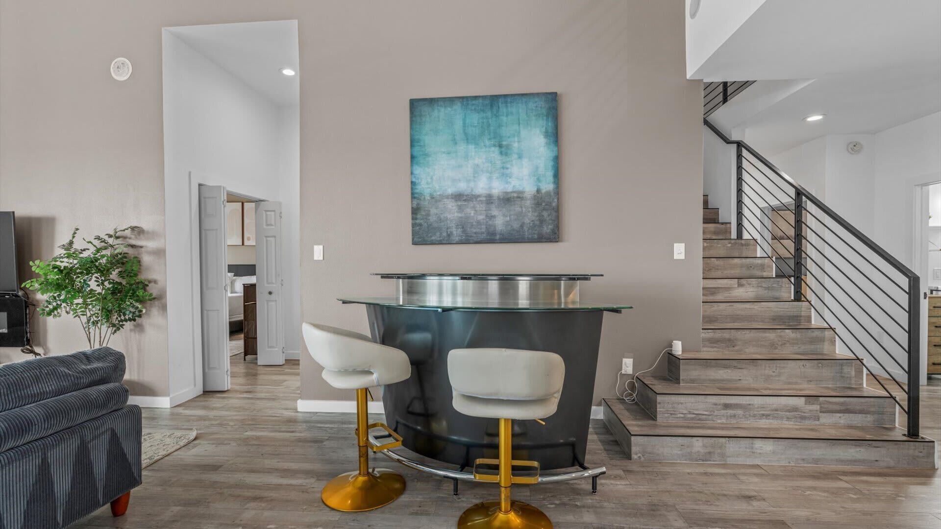 A modern kitchen with a bar area, a staircase, and a view of the living room.