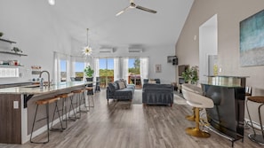A spacious kitchen with a bar area, a dining area with a sofa, and a large window offering a view. - Lakefront Retreat w Pool, Hot Tub & Stunning Views (Lakeway)