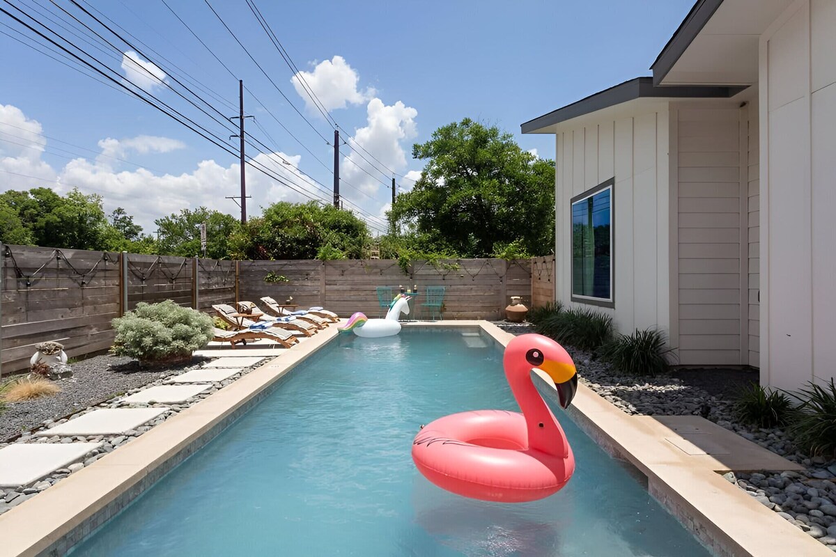 Une piscine avec des bouées en forme de cygne gonflable, une clôture en bois et une maison avec une fenêtre.