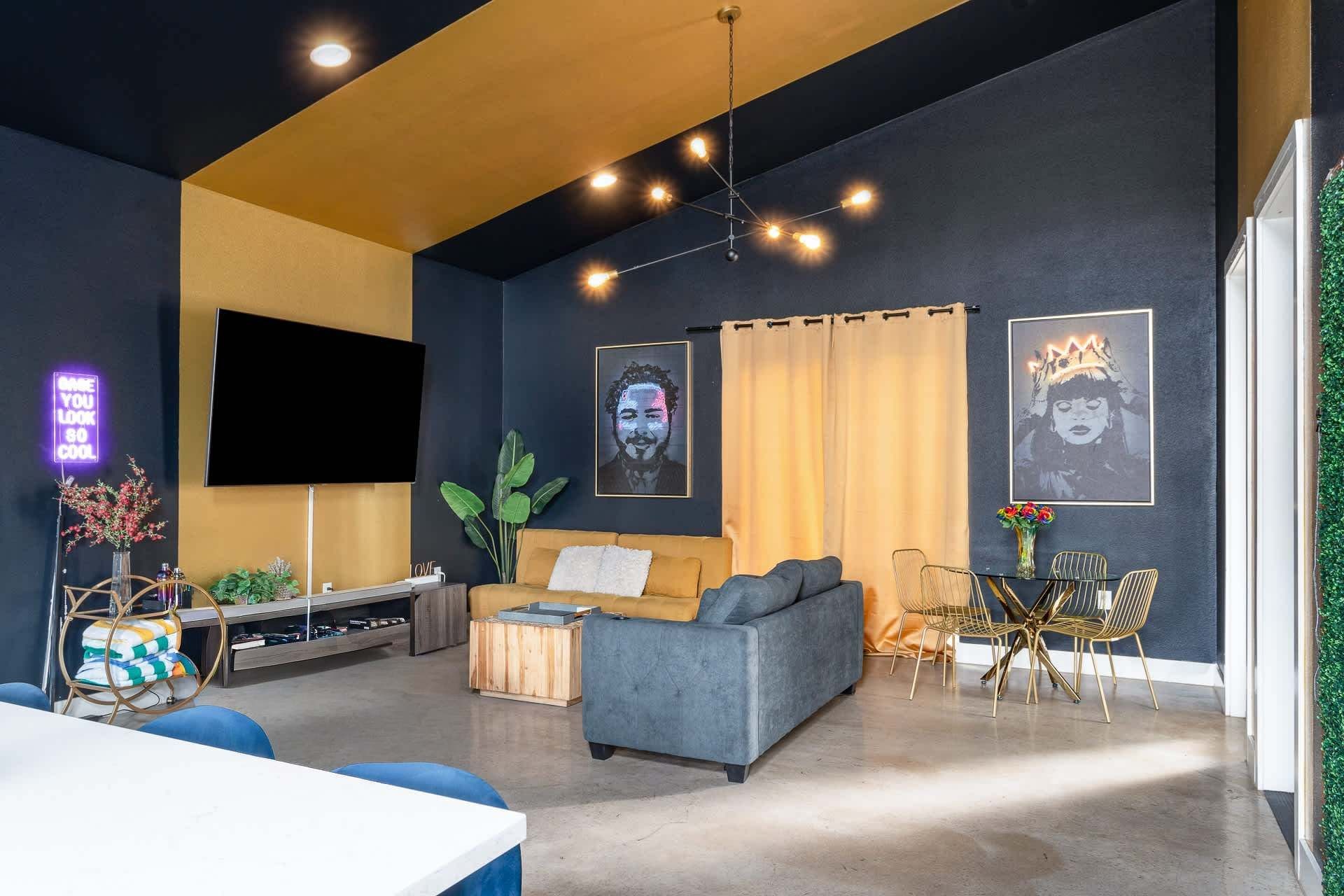 Una sala moderna con un sofá, televisor, comedor con sillas y obras de arte en las paredes.