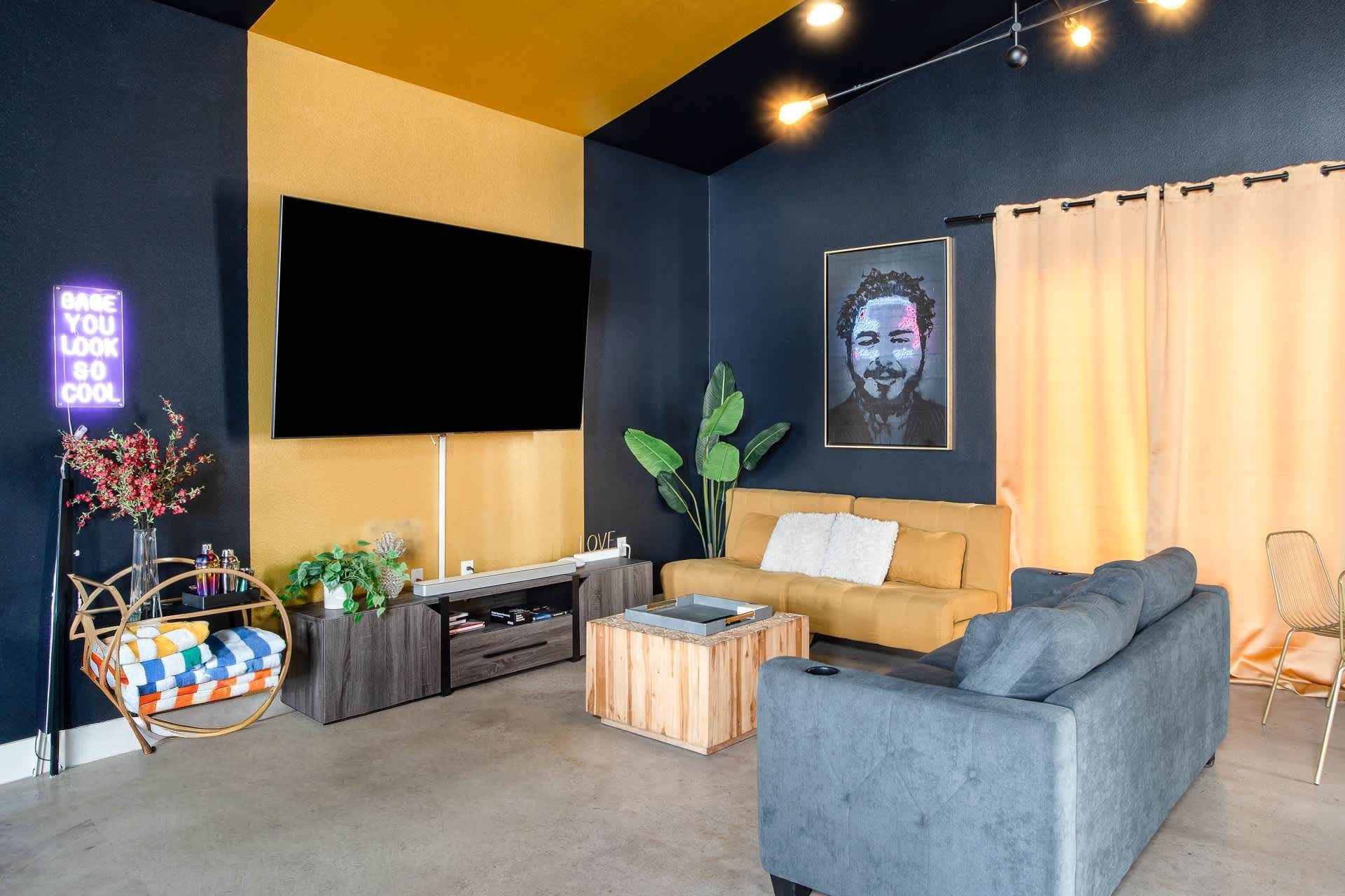 Un salon moderne avec un canapé, une table basse, un téléviseur et des plantes décoratives.