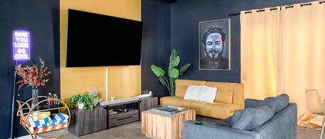 Un salon moderne avec un canapé, une table basse, un téléviseur et des plantes décoratives.