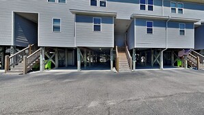 Un edificio a più piani con un'area di parcheggio coperta e una scala che conduce all'ingresso.