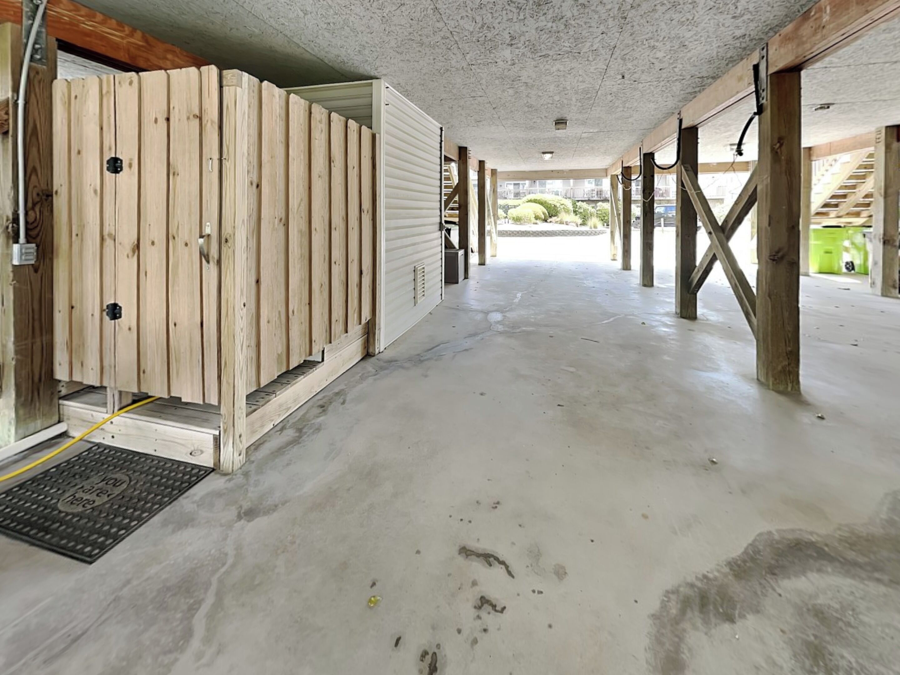 Un amplio espacio interior con piso de concreto, paredes de madera y una escalera visible al fondo.