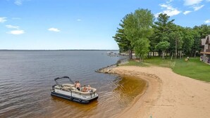 Un lago con un bote, una playa de arena y un edificio de fachada de piedra.
