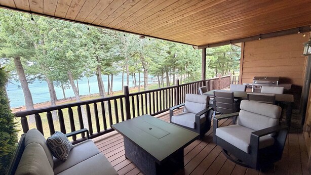 Un espacio de estar al aire libre techado con vista al agua, muelle de madera y mobiliario exterior.