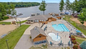 Una cabaña junto al lago con piscina, mobiliario de exterior y muelle.