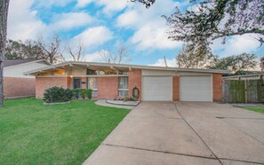 A single-story house with a garage, a front lawn, and a wooden fence. - Sleeps 16+ | Game Room + 75” TV | Fire Pit + BBQ (Houston)