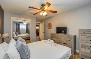 A bedroom with a bed, a ceiling fan, a dresser, and a television. - Sleeps 16+ | Game Room + 75” TV | Fire Pit + BBQ (Houston)