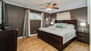 Une chambre à coucher avec un lit en bois, un ventilateur de plafond, une table de chevet et une commode.