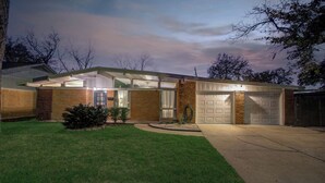 Une maison moderne avec un garage, une pelouse bien entretenue et un ciel dégagé.
