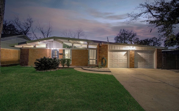 Une maison moderne avec un garage, une pelouse bien entretenue et un ciel dégagé.