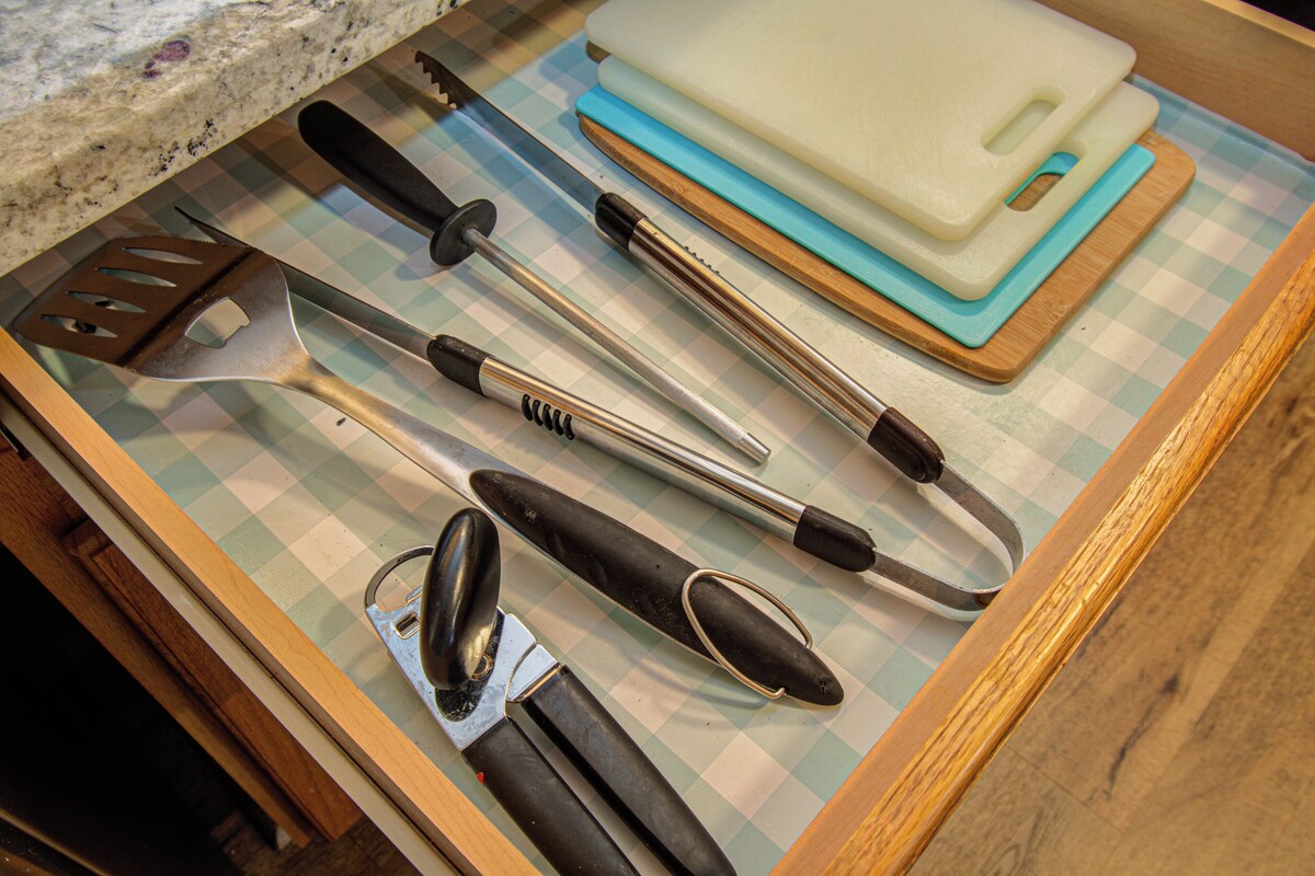 A kitchen counter with various utensils and a cutting board.