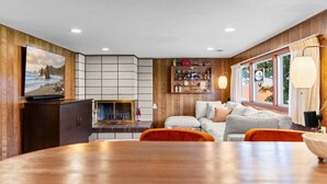 A living room with a fireplace, a television, a sofa, and a dining table.