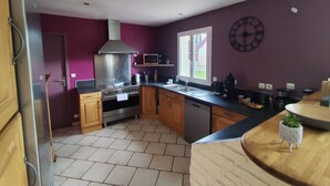 A kitchen with a stainless steel range hood, wooden cabinets, a microwave, and a clock on the wall. - La Sandillonnaise, Holiday home close to all amenities 15 min from Orléans (Sandillon)