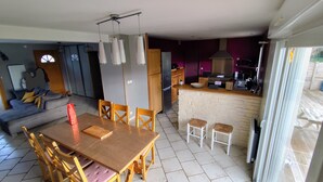 A dining area with a wooden table and chairs, a kitchen with a stove, and a living room with a sofa. - La Sandillonnaise, Holiday home close to all amenities 15 min from Orléans (Sandillon)
