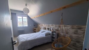 A bedroom with a bed, a hanging chair, a window, and a wooden wall. - La Sandillonnaise, Holiday home close to all amenities 15 min from Orléans (Sandillon)