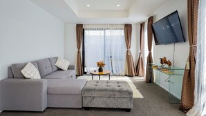 Ein modernes Wohnzimmer mit einem grauen Sofa, einem Glastisch und einem flachbildfernseher an der Wand.