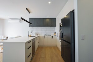 A modern kitchen with white cabinetry, a black refrigerator, and a tiled backsplash.