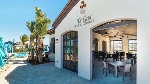 Eine Bar und ein Lounge-Bereich mit Außenplätzen und einem Pool im Hintergrund.