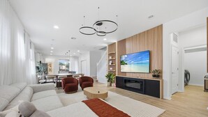 Ein modernes Wohnzimmer mit einer Eckcouch, einem Flachbildfernseher und einer Wand mit Holzpaneelen.
