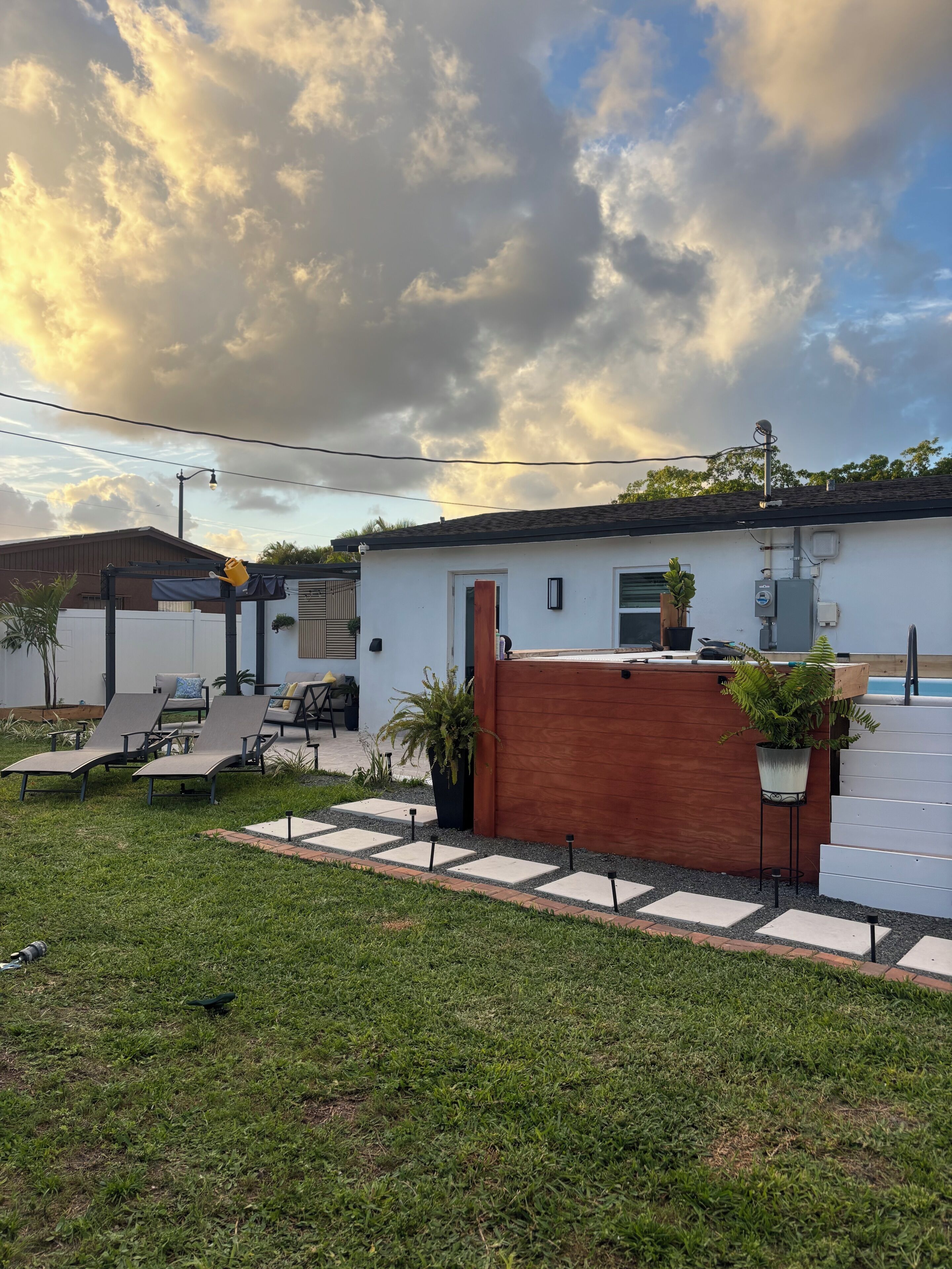 Ein Garten mit Pool, Liegestühlen und einer Holzterrasse.