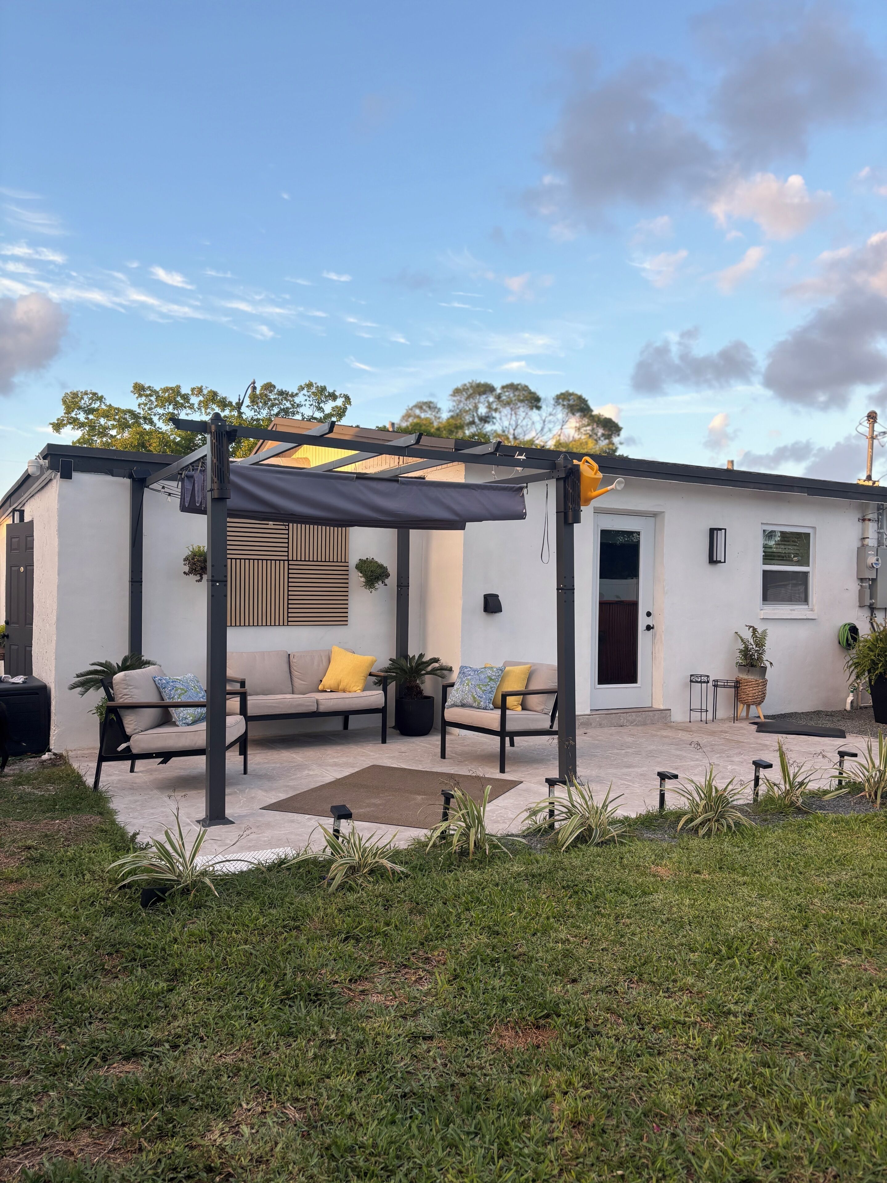 Ein Haus mit überdachter Terrasse, einer Couch und einem kleinen Tisch.