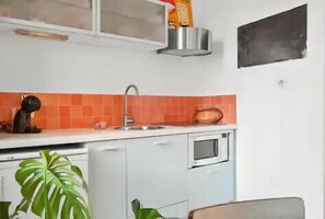 Cocina pequeña equipada con un lavamanos, un escurreplatos y un microondas.