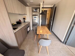 Une cuisine compacte comprenant une table et des chaises, un four à micro-ondes et un réfrigérateur.
