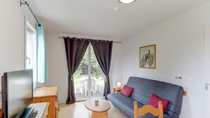 Ein Wohnzimmer mit Fernseher, Holzmöbeln, einer Couch und einem Tisch mit Blumenvase.