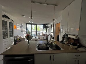 A modern kitchen with a central island, a dining area with a sofa, and a view through large windows. - 5 minute walk to BC Place | Stylish Apartment | Sleeps 3 (Vancouver)
