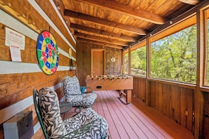 A wooden deck with a dartboard, a foosball table, and a view of the forest. - Perfect 2-bedroom cabin with AC in beautiful Suwanee (Sevier County)