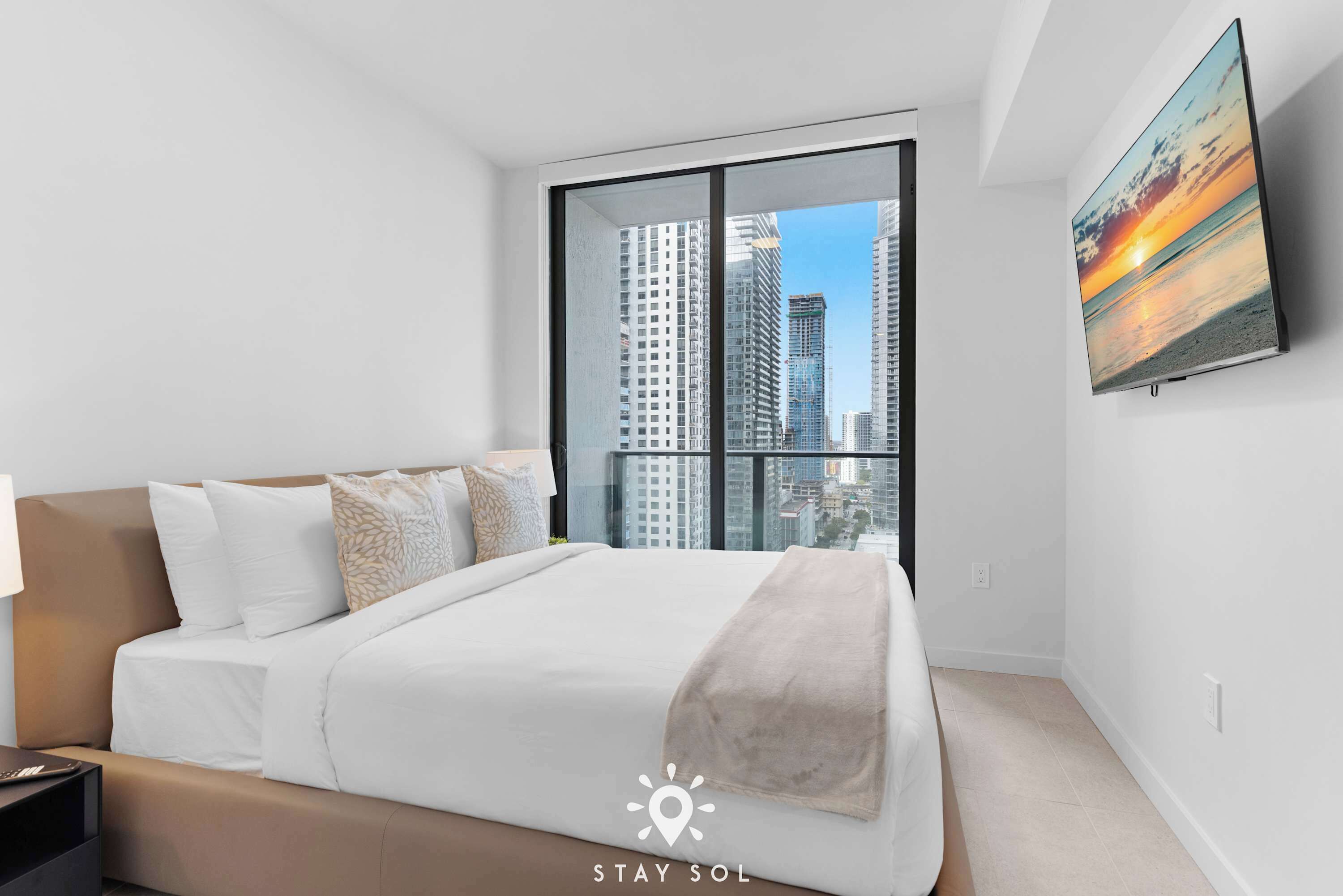 A modern bedroom with a large window, a bed, and a painting on the wall.