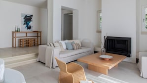 A modern living room with a sofa, coffee table, and fireplace. - Elies Resort (Sifnos)