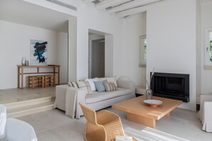 A modern living room with a sofa, coffee table, and fireplace. - Elies Resort (Sifnos)