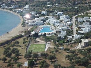 Een woongebied aan de kust met witte gebouwen, een zwembad en een tennisbaan.