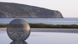 A spherical sculpture on a tiled surface with a coastal view in the background. - Elies Resort (Sifnos)