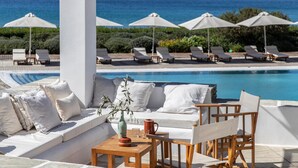 A poolside area with lounge chairs, umbrellas, and a seating area with cushions and a table. - Elies Resort (Sifnos)