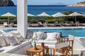 A poolside area with lounge chairs, umbrellas, and a seating area with cushions and a table. - Elies Resort (Sifnos)
