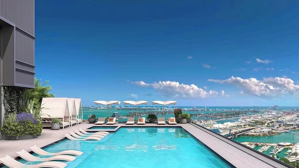 A rooftop infinity pool with lounge chairs and umbrellas, overlooking a cityscape and coastline. - Resort Living & Peaceful Balcony Mornings – 1BR (Miami)