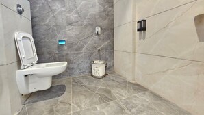 A modern bathroom with a toilet, bidet, and trash bin. - TrueLife SRB Suites (Tirupati)