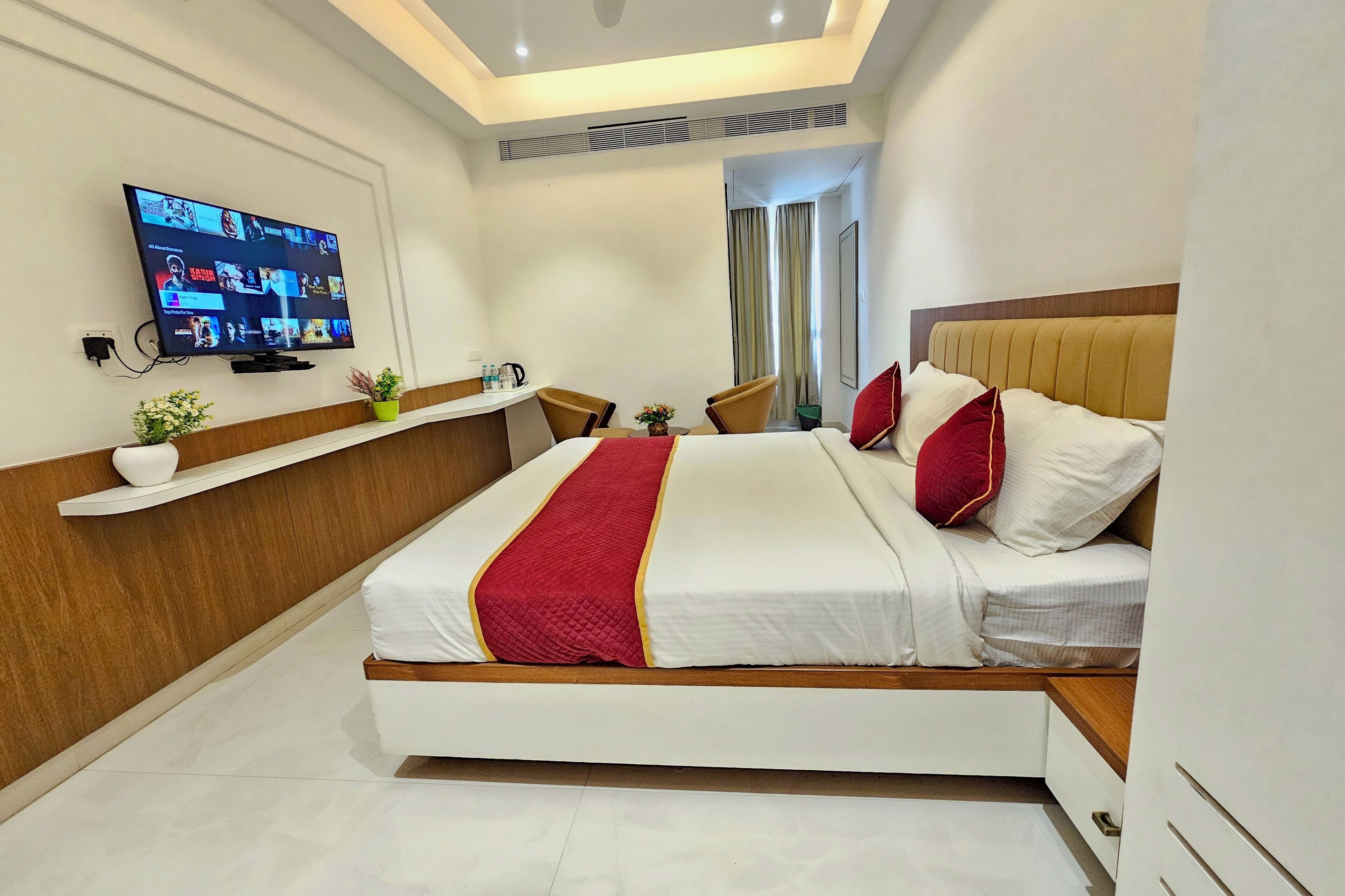 A hotel room with a bed, a TV mounted on the wall, a desk, and a chair.